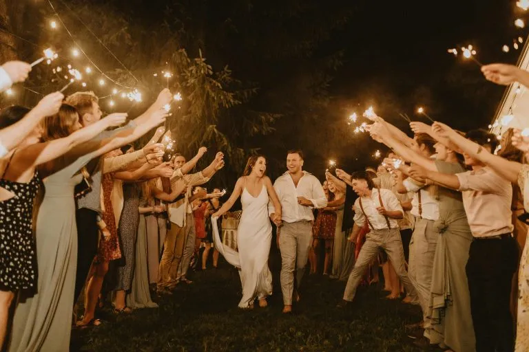 Novios saliendo entre invitados con bengalas en una boda de noche