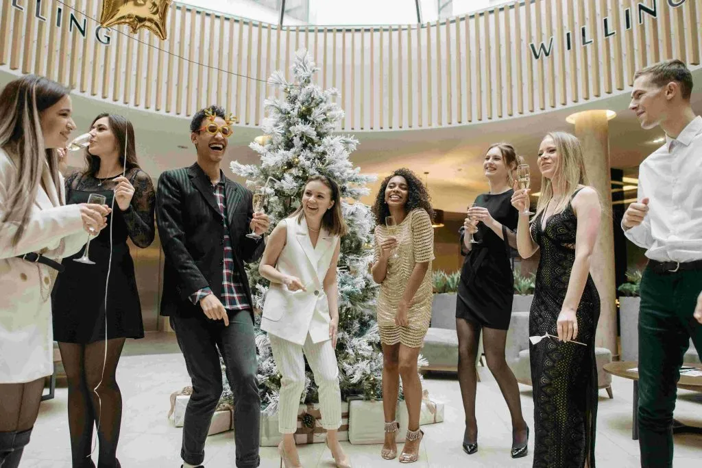 Coworkers toasting next to a Christmas tree at the company party