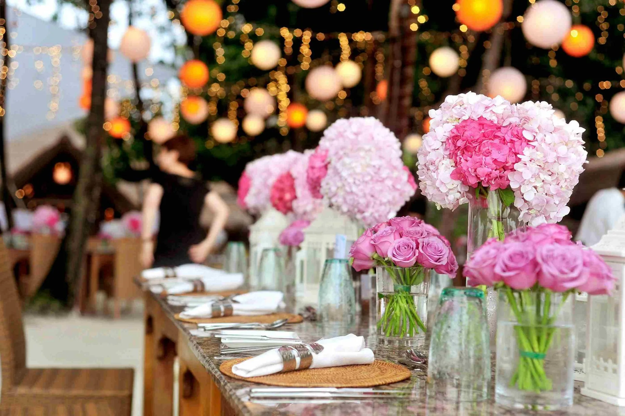 Outdoor wedding table with pink hydrangeas and hanging lanterns